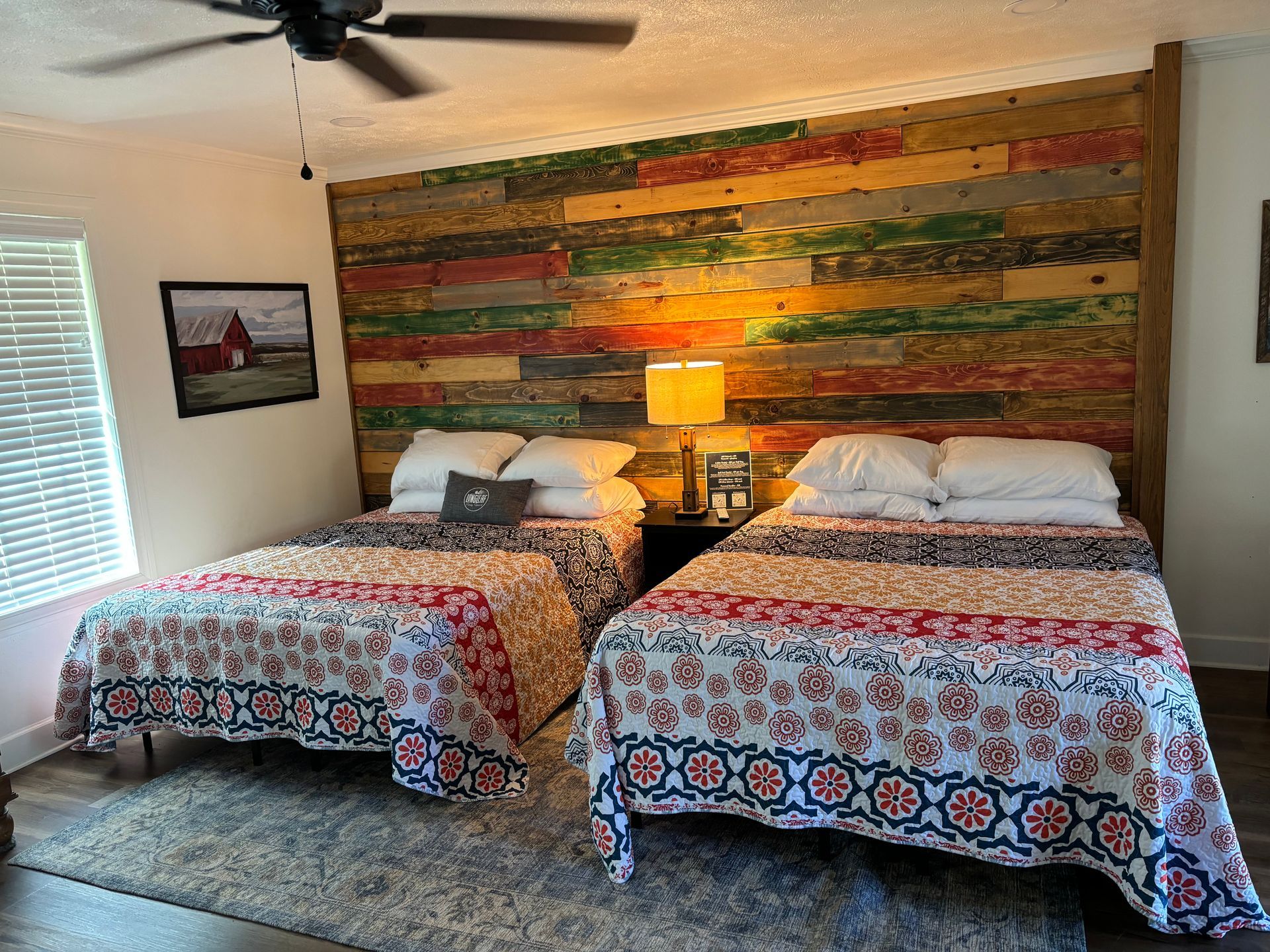 A bedroom with two beds , a ceiling fan and a wooden wall.