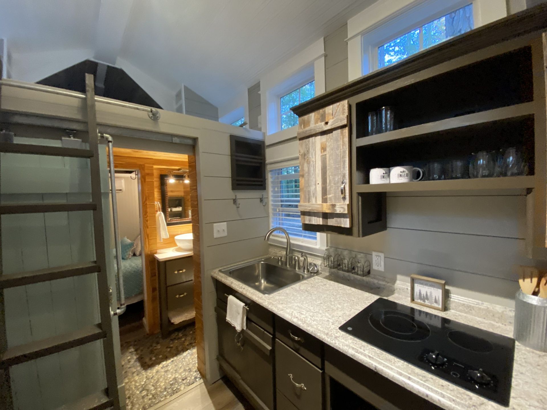 A kitchen in a small house with a sink , stove , and ladder.