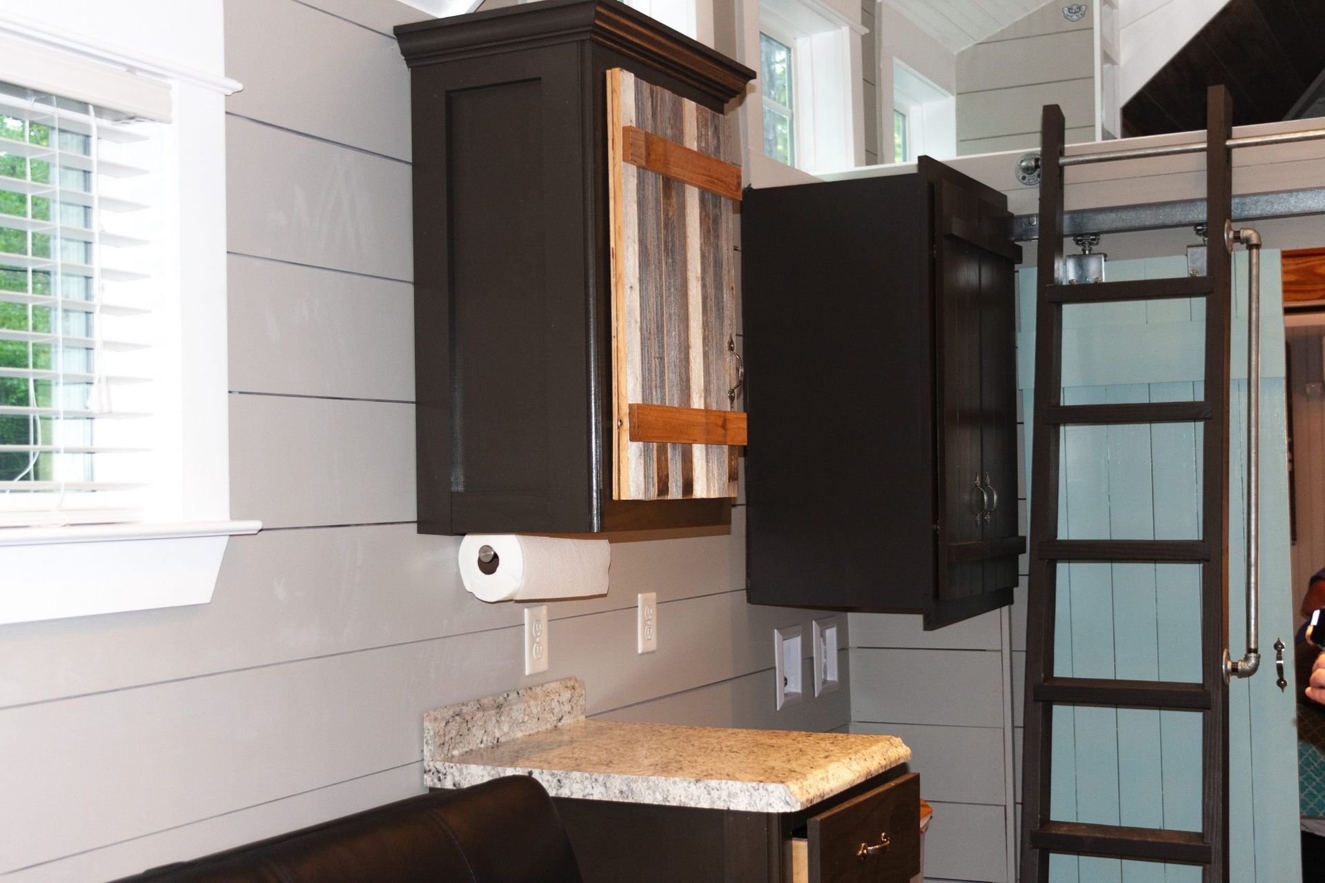 A kitchen in a small house with a ladder and a couch.