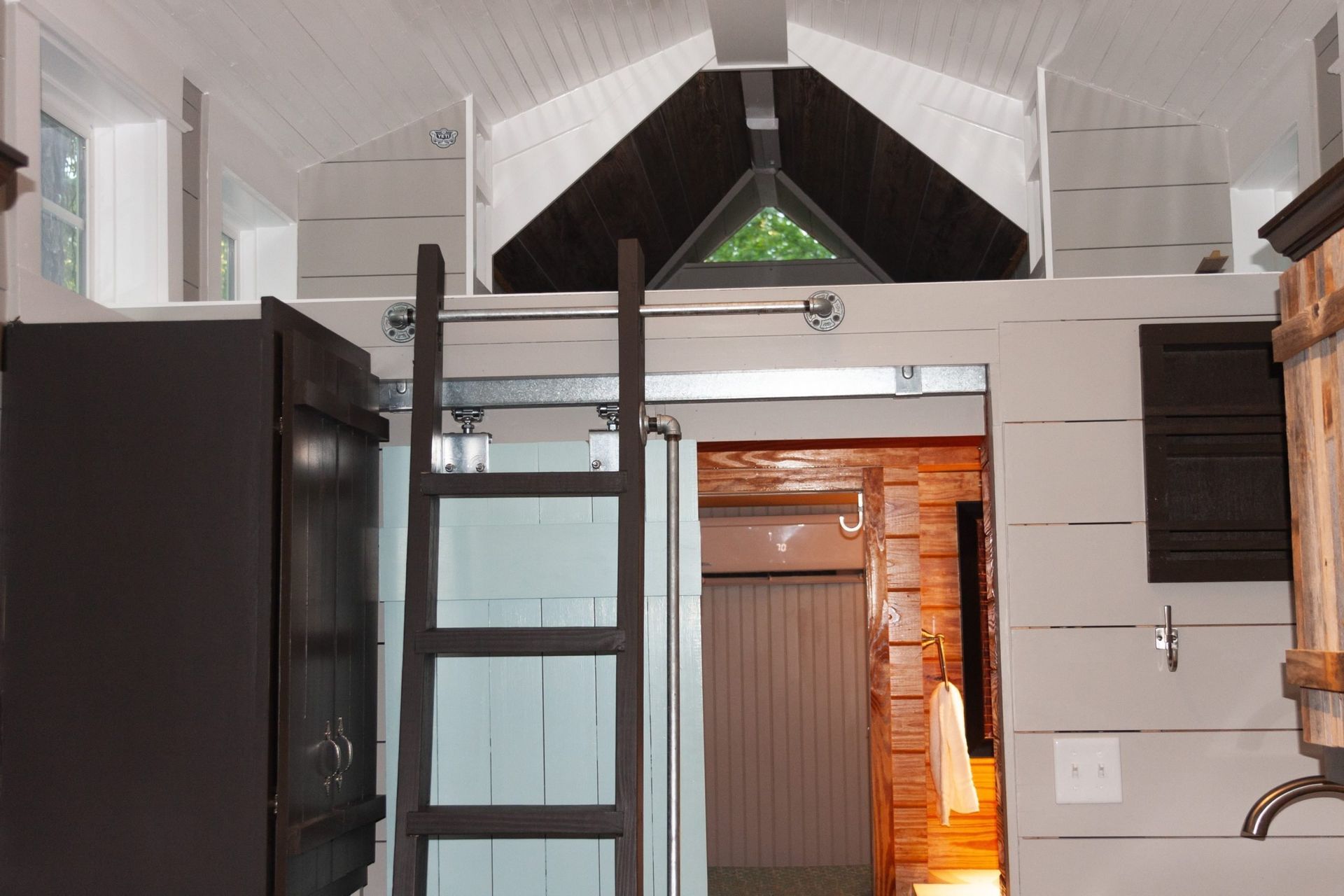 A ladder is leading up to a loft in a small house.