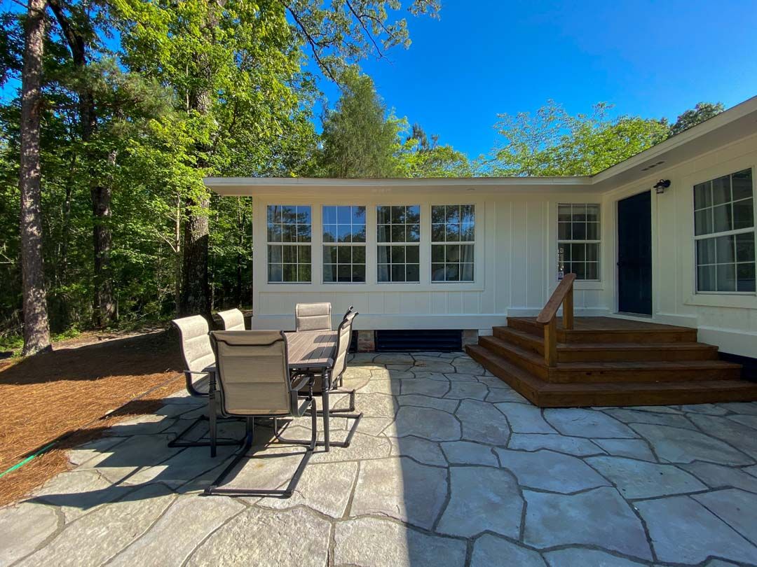 There is a patio with a table and chairs in front of a house.