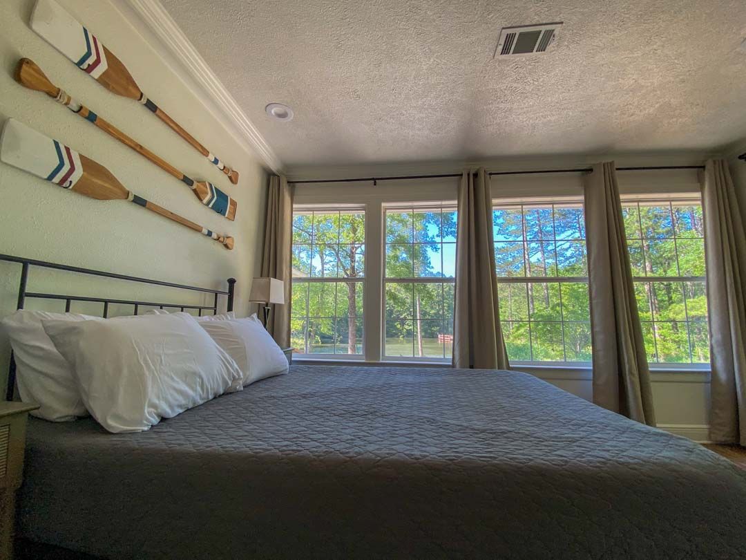 A bedroom with a king size bed and three windows.