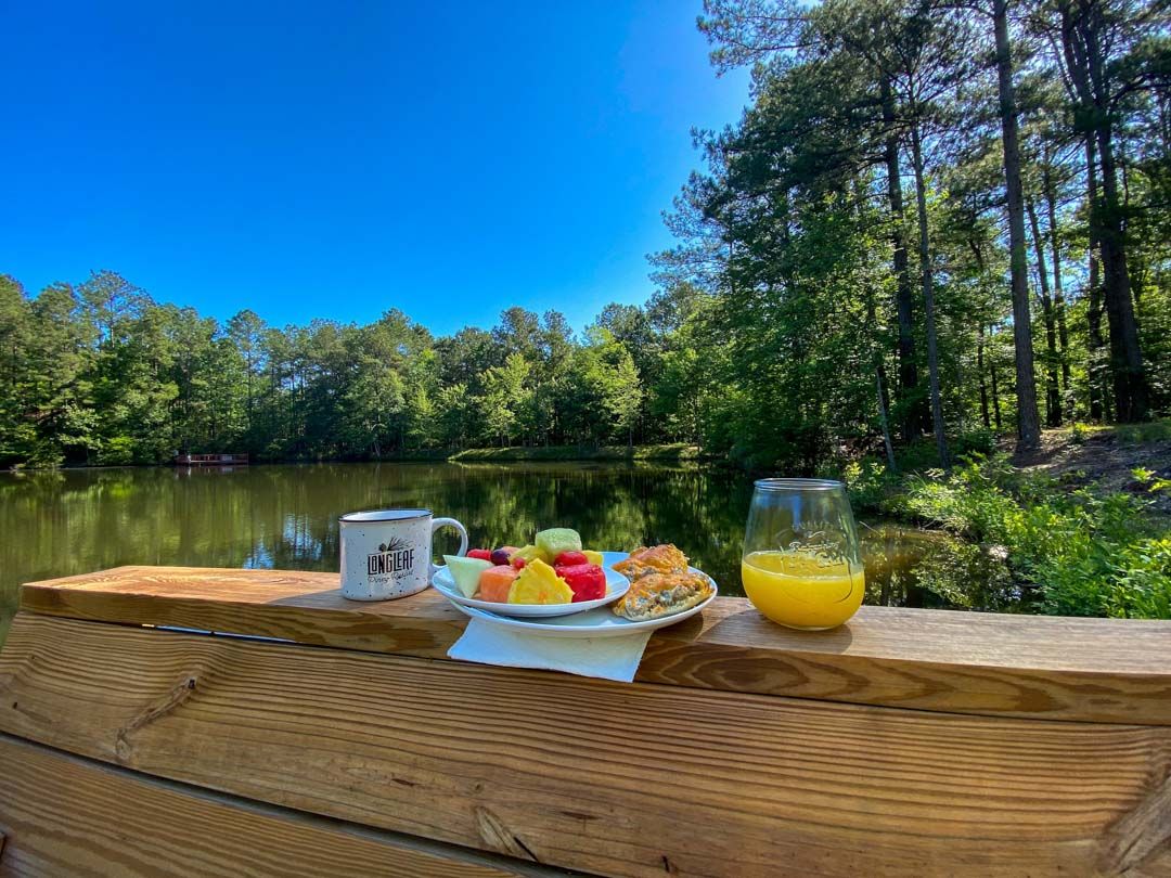 A wooden table with a plate of food and a glass of orange juice on it.