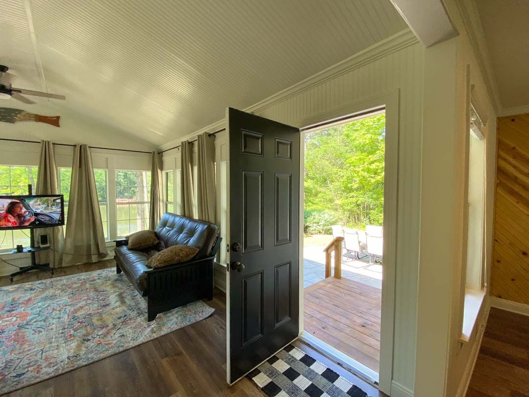 A living room with a black couch and a black door leading to a porch.