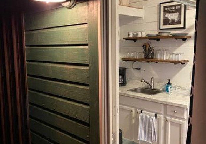 A kitchen with a sink and a picture of a cow on the wall.