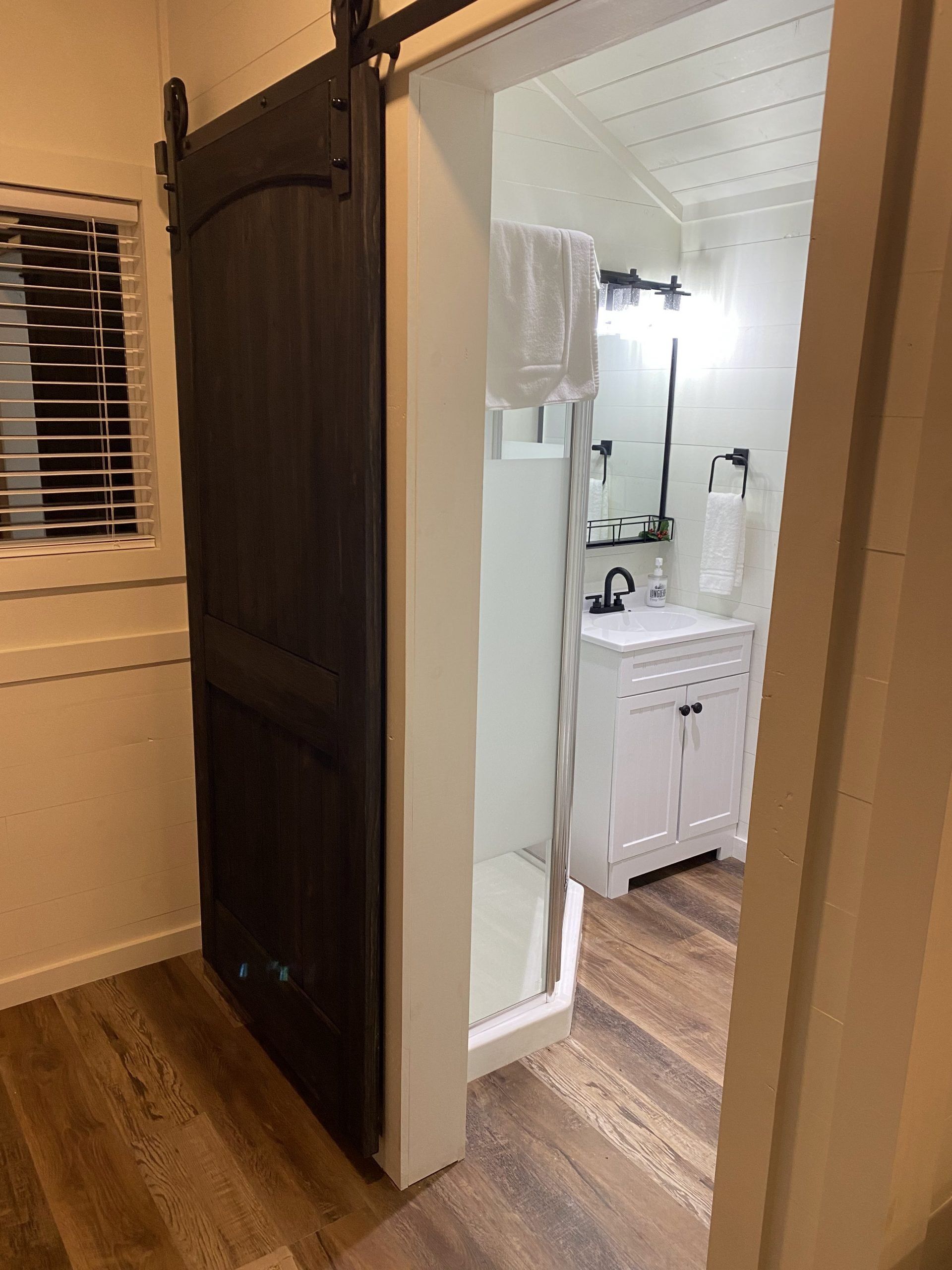 A bathroom with a sliding barn door and a sink.
