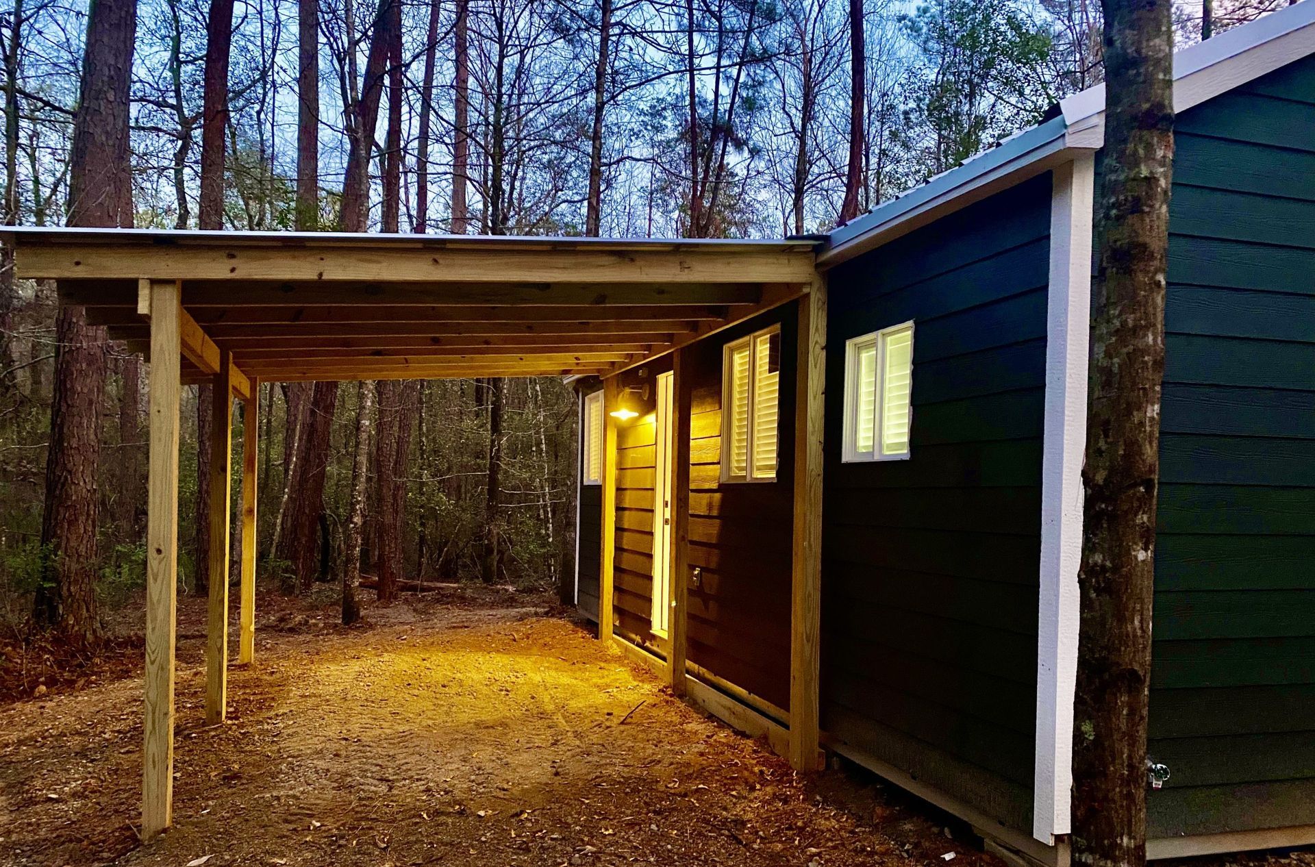 A small house with a carport in the woods.
