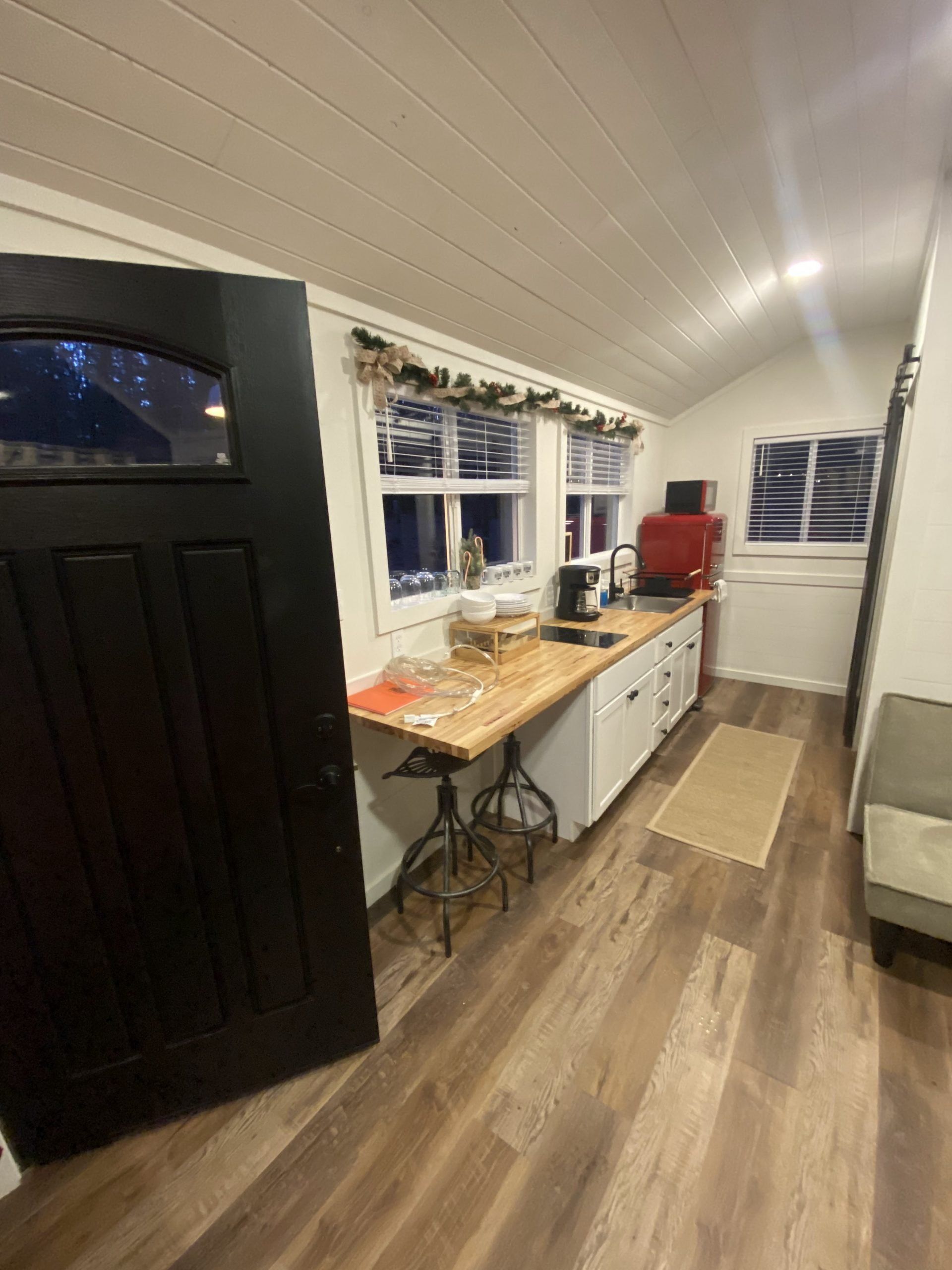 A kitchen with a black door and a wooden counter top.