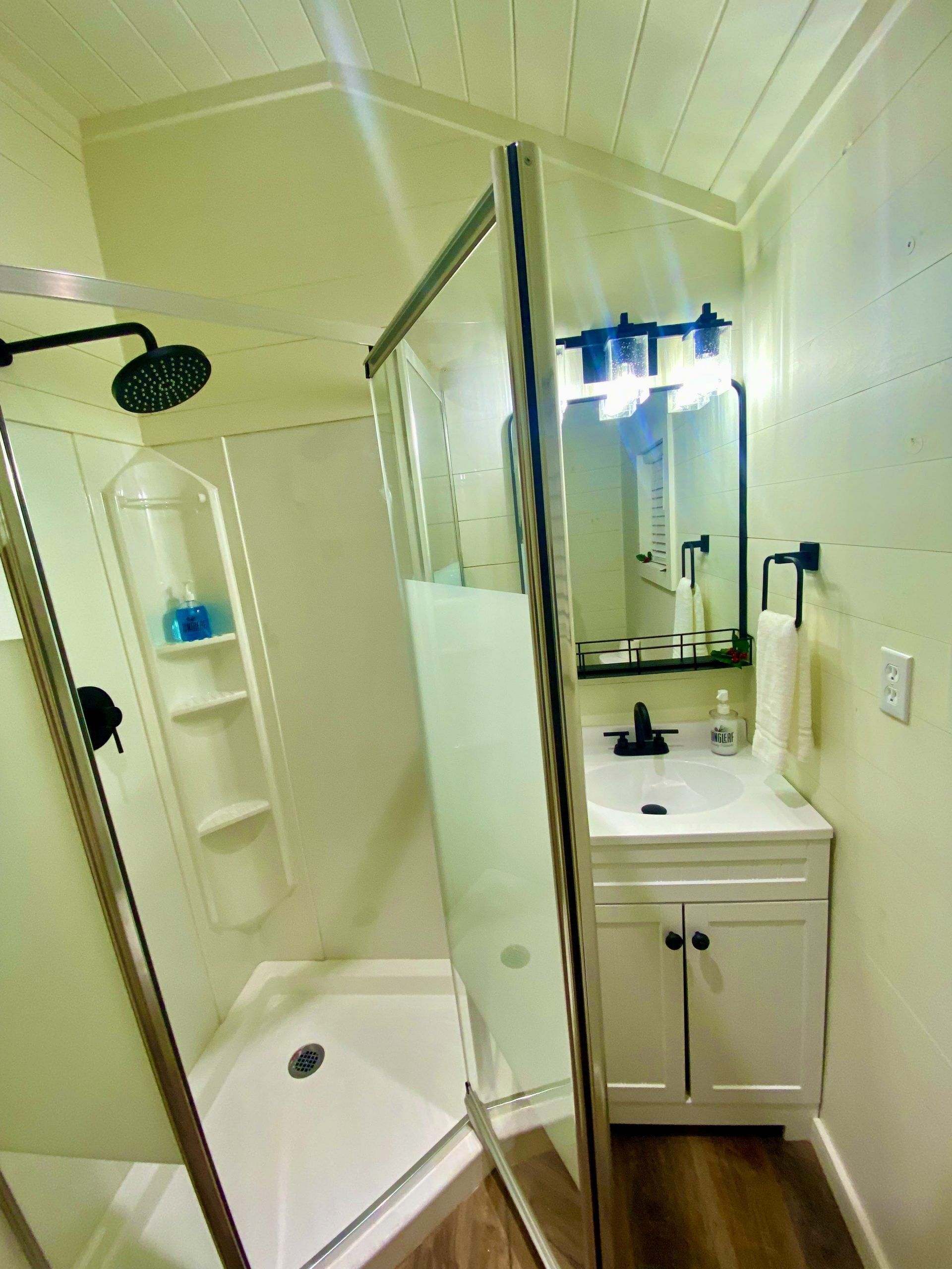 A bathroom with a shower , sink and mirror