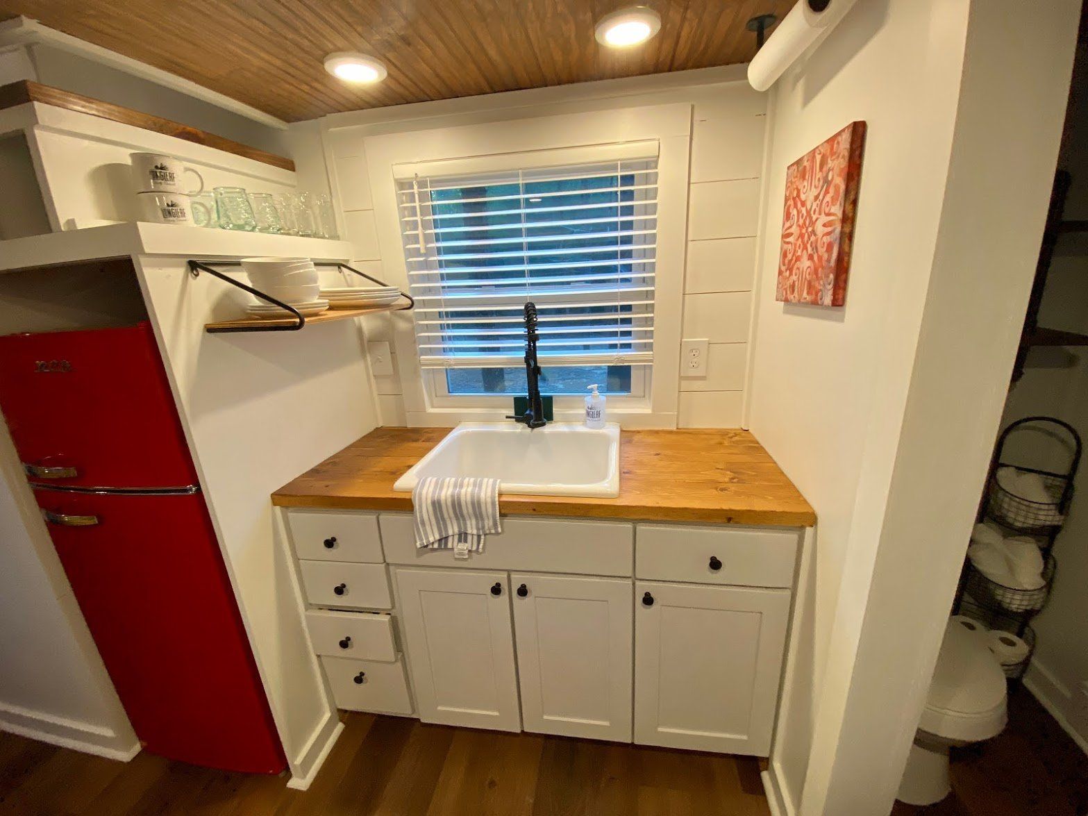 A kitchen with a sink and a red refrigerator.