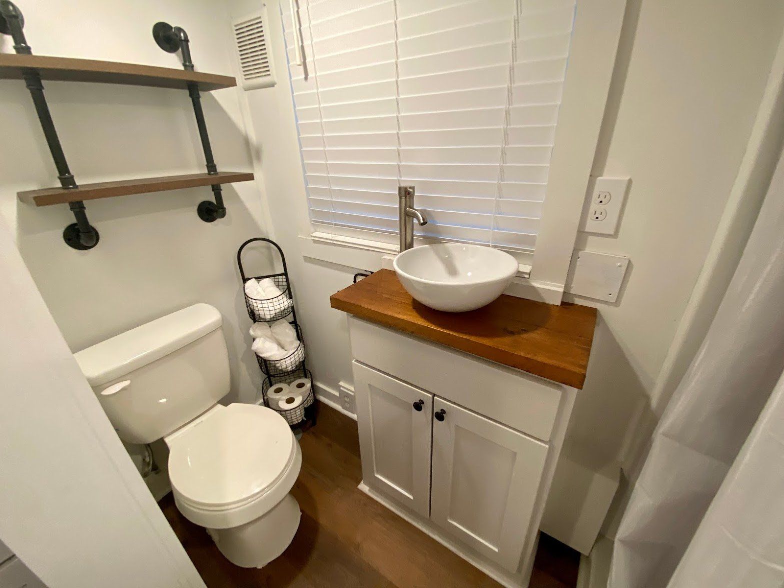 A bathroom with a toilet , sink and window.