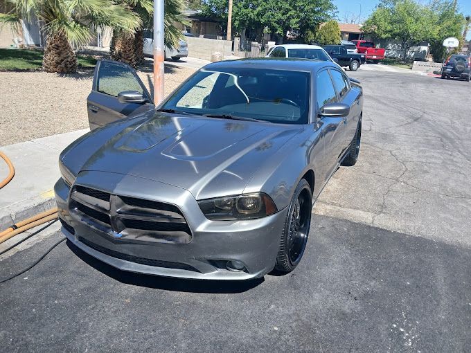 A gray dodge charger is parked on the side of the road