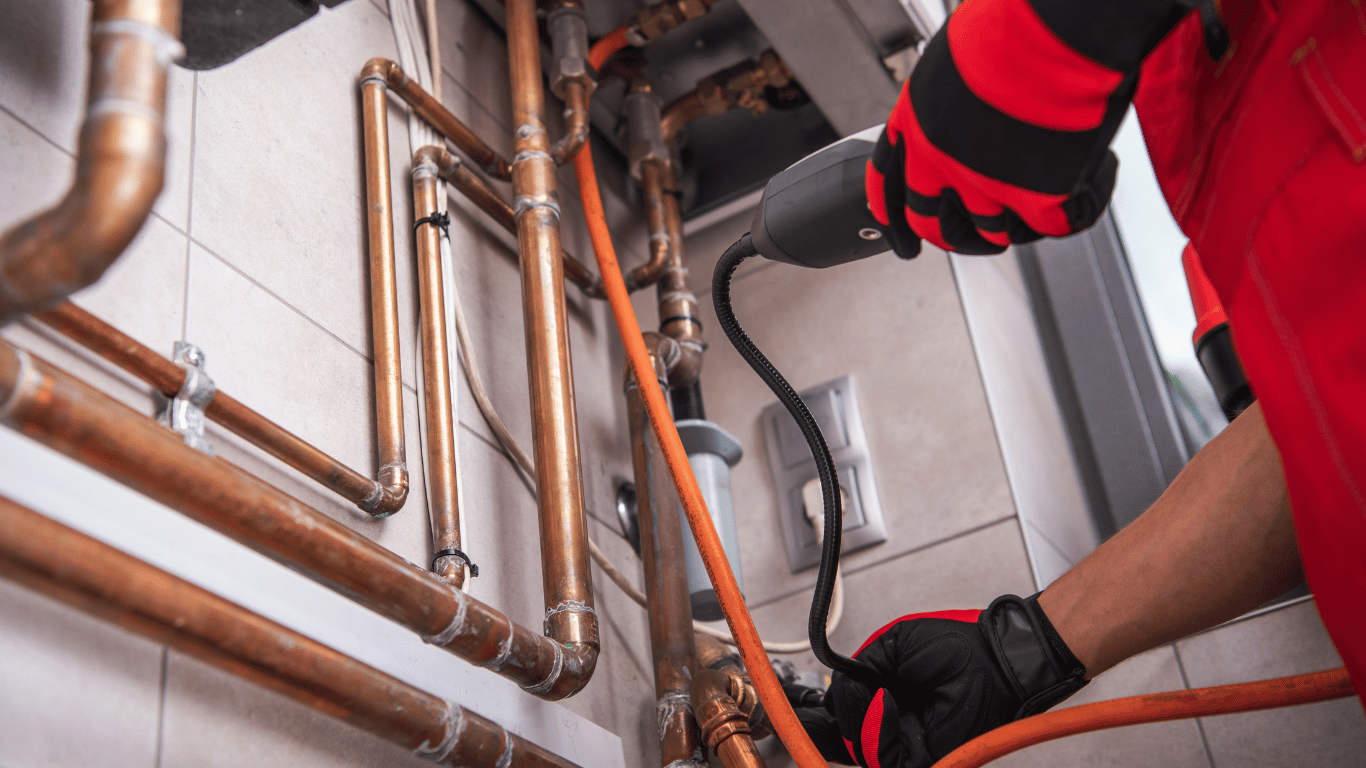 A plumber is working on a pipe with a tool, focusing on HVAC boiler repair to restore heating system functionality.