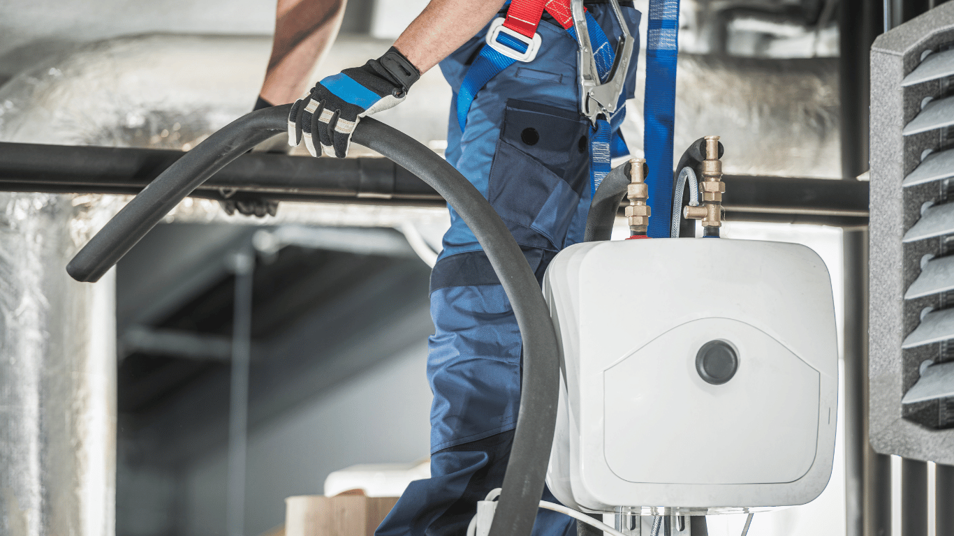 A man is using a vacuum cleaner to clean a pipe, maintaining indoor air quality with advanced cleaning techniques.