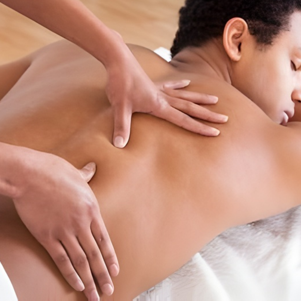 Hands massaging a person's oiled back on a massage table.