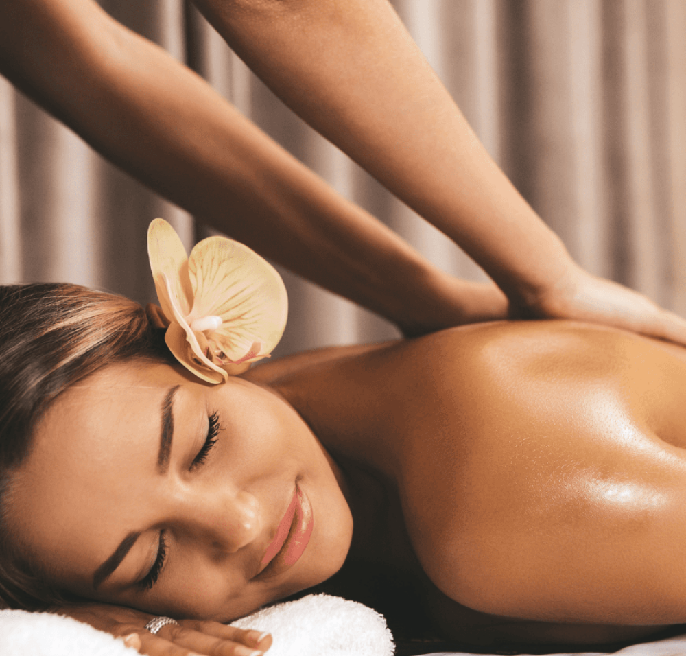 Hands massaging a person's oiled back on a massage table.