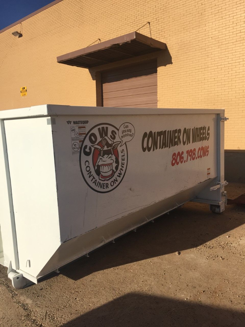 Woman in straw hat smiles, holding wine glass near a lake.