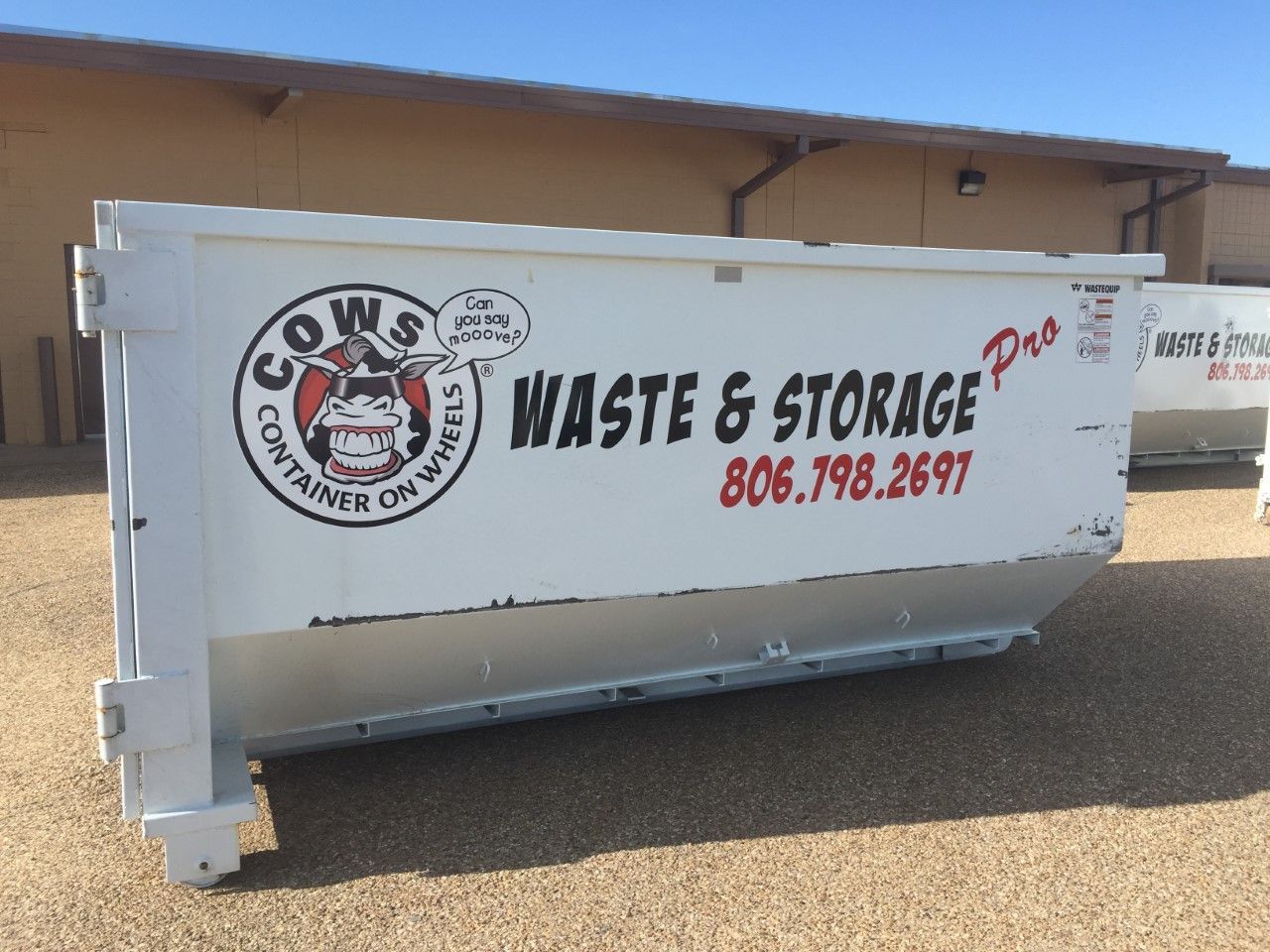Woman in straw hat smiles, holding wine glass near a lake.