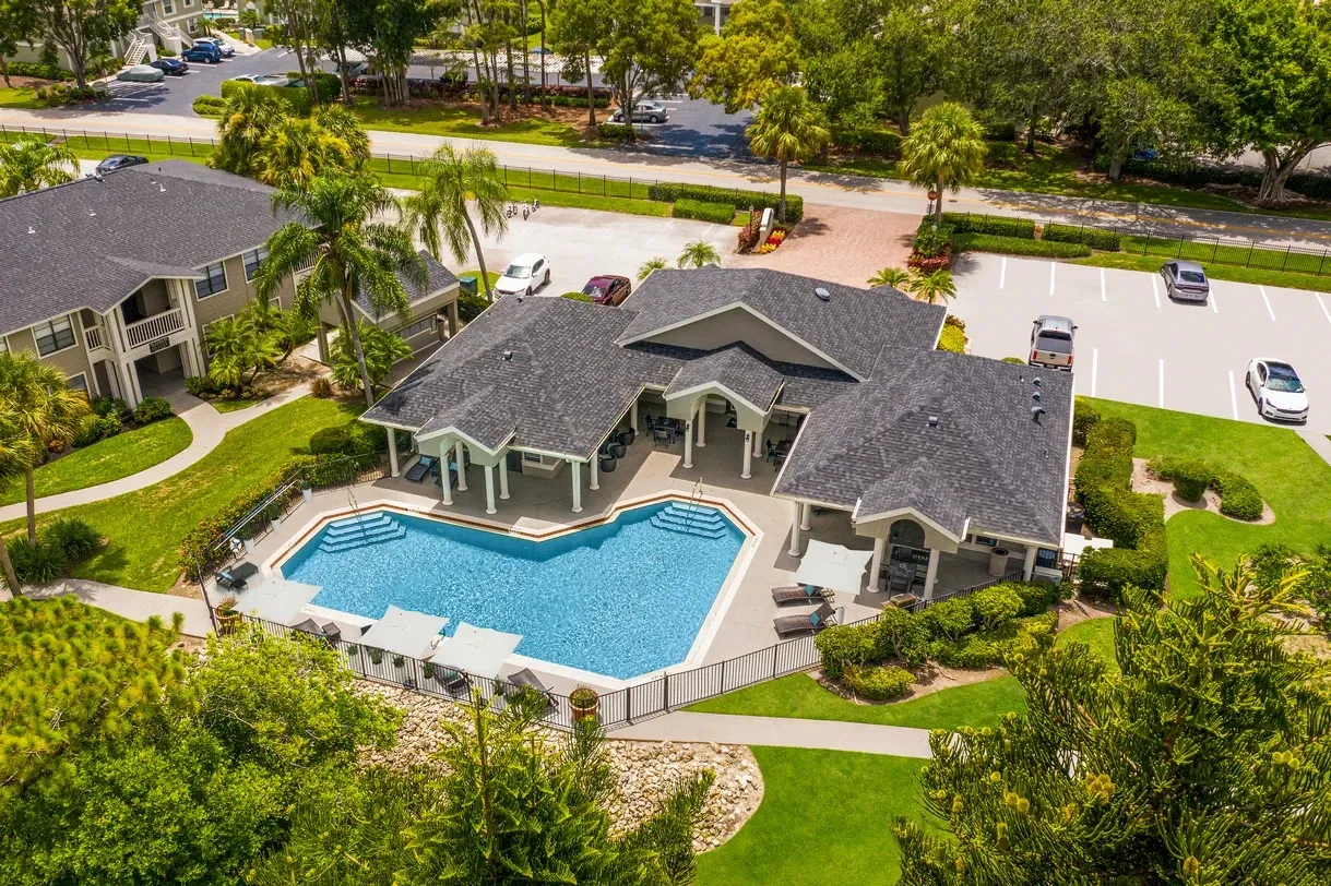Aerial view of a swimming pool with a building and surrounding landscaping.