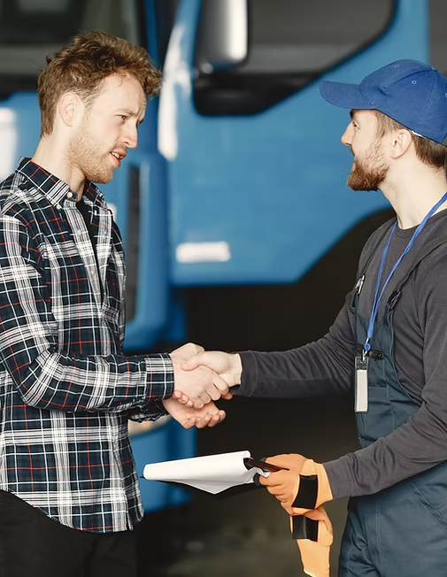 Two men are shaking hands in front of a blue truck.