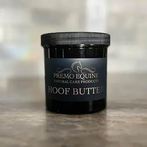 A jar of hoof butter is sitting on a wooden table.