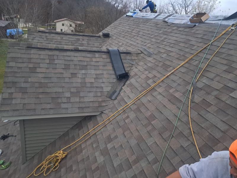 Roof being replaced with workers shingling 