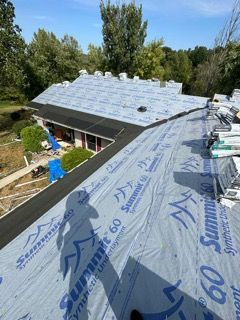 The roof of a house is being covered with a roofing material.