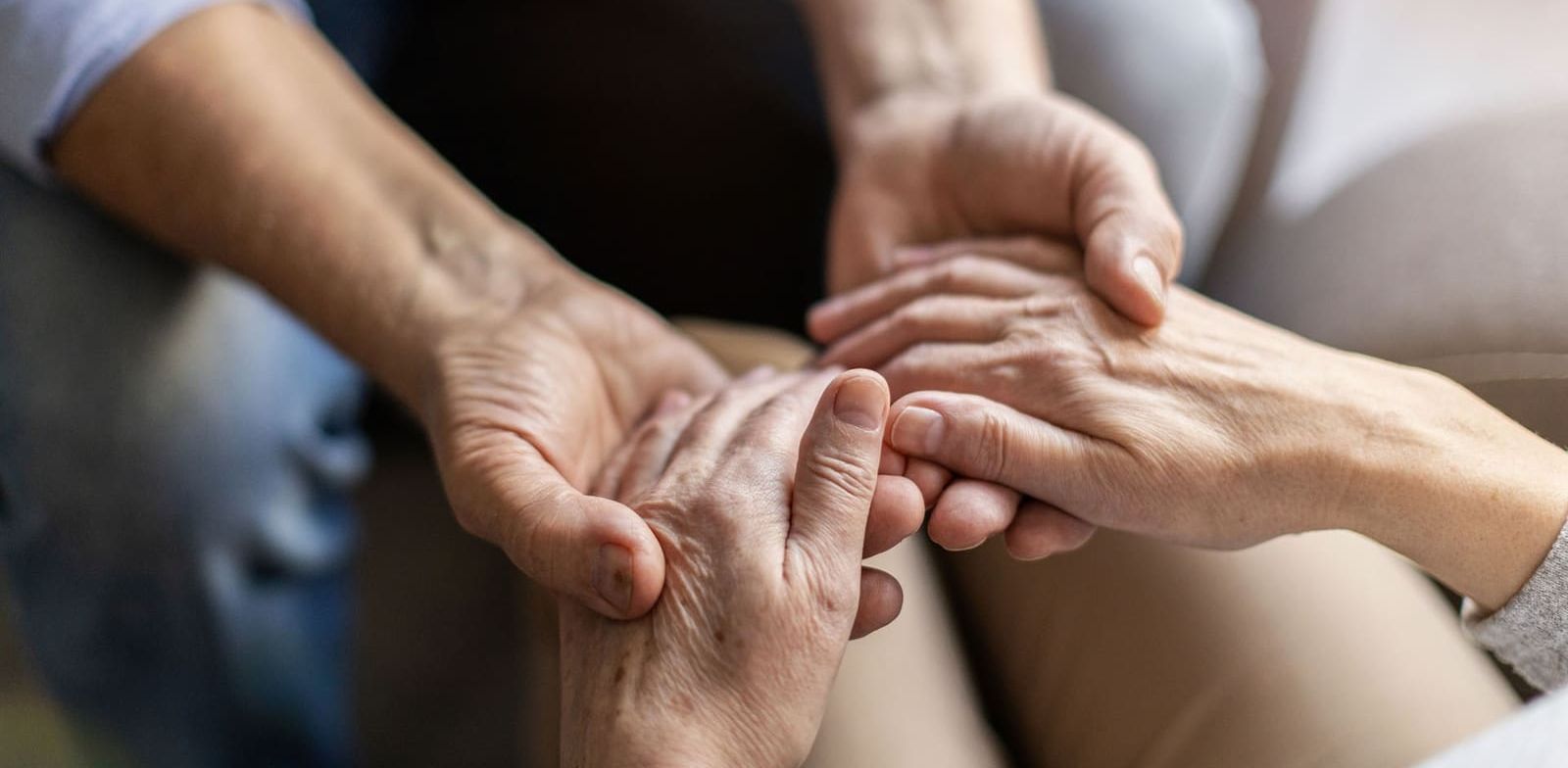 A man and a woman are holding hands while sitting on a couch.