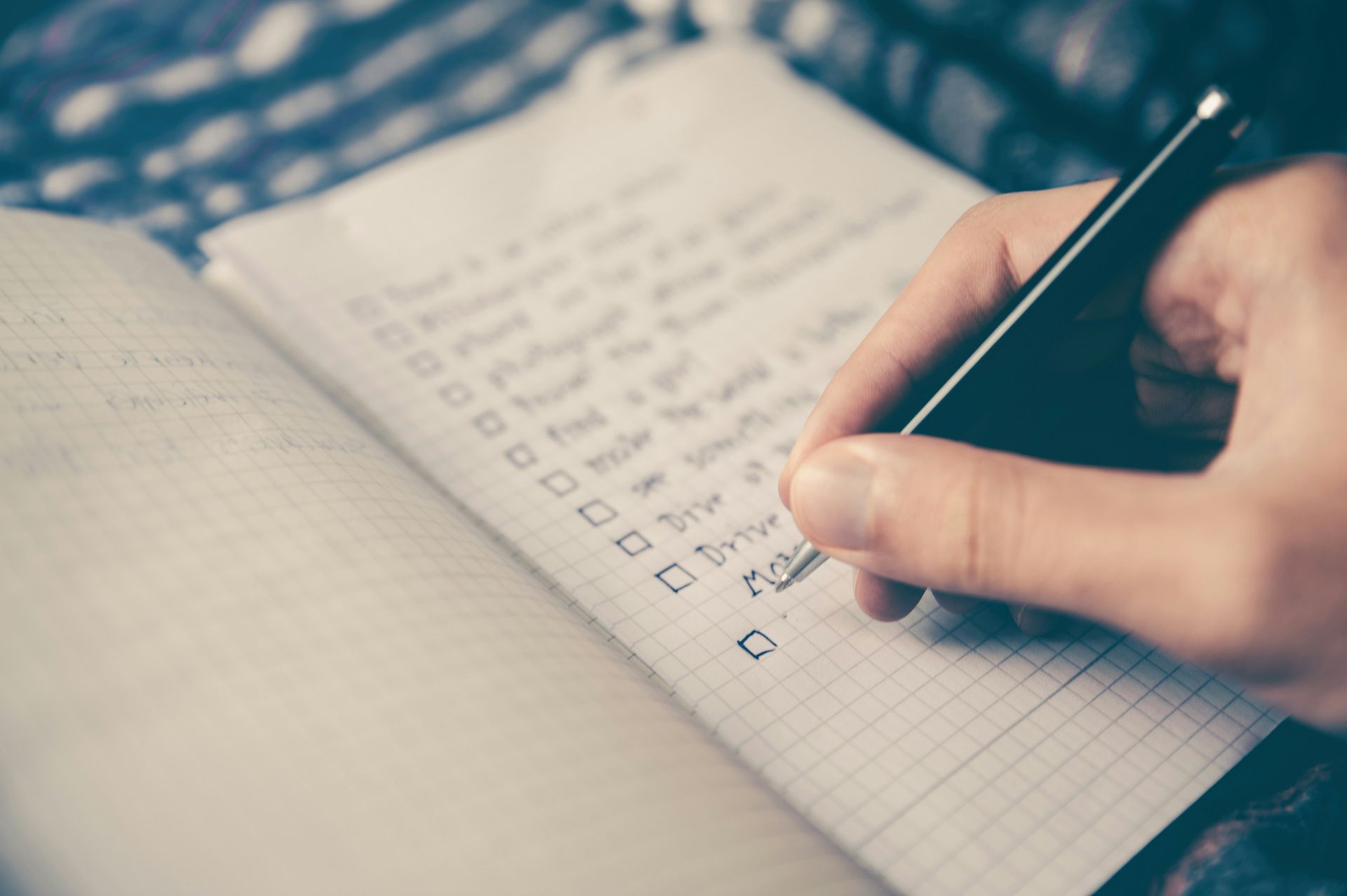 A person is writing on a checklist in a notebook.