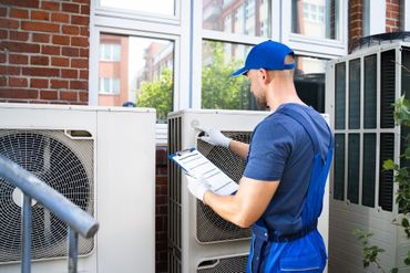 A man is cleaning an air conditioner on a wall.