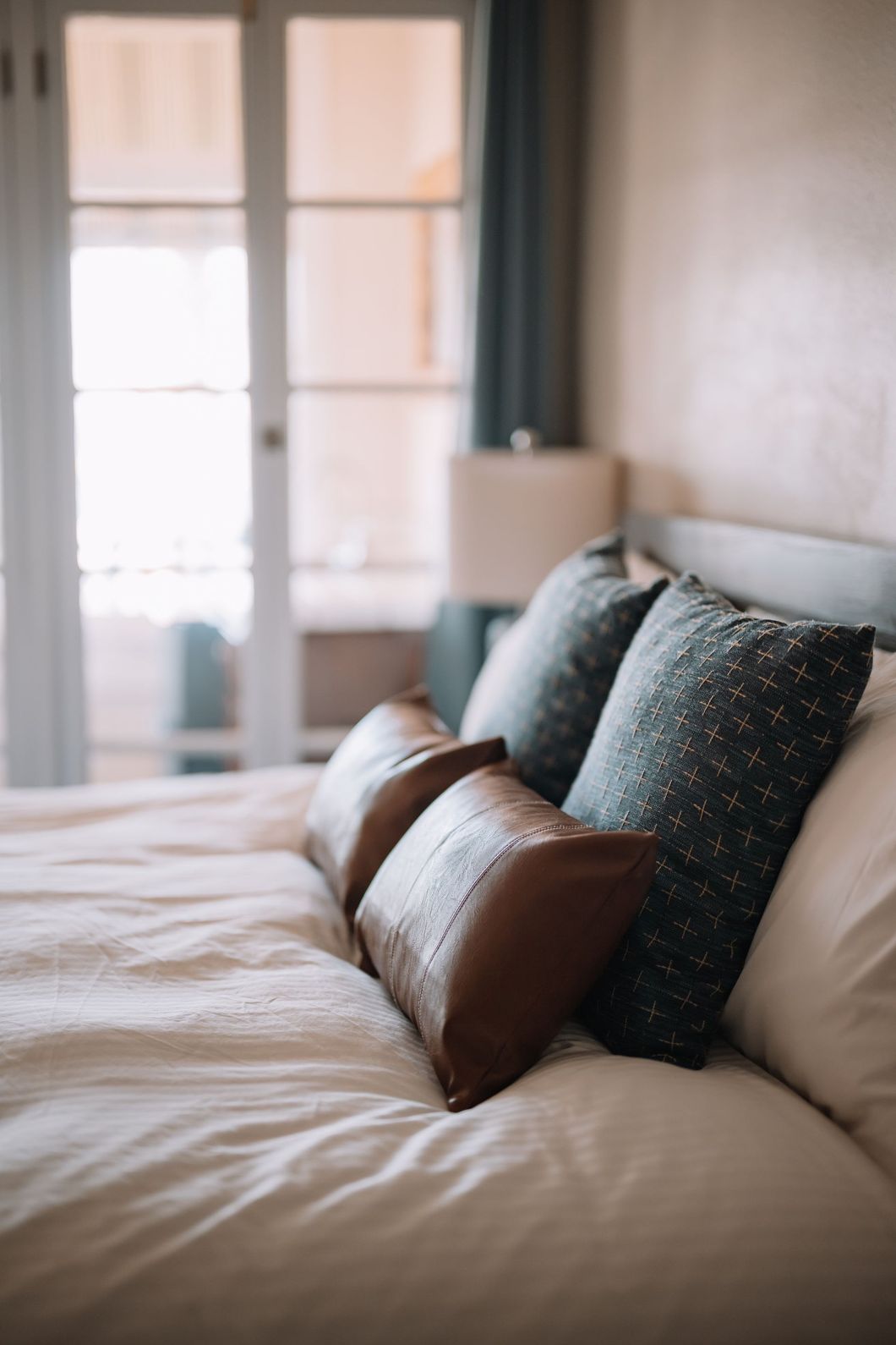 a bed with white sheets and blue pillows in a bedroom with a lamp .