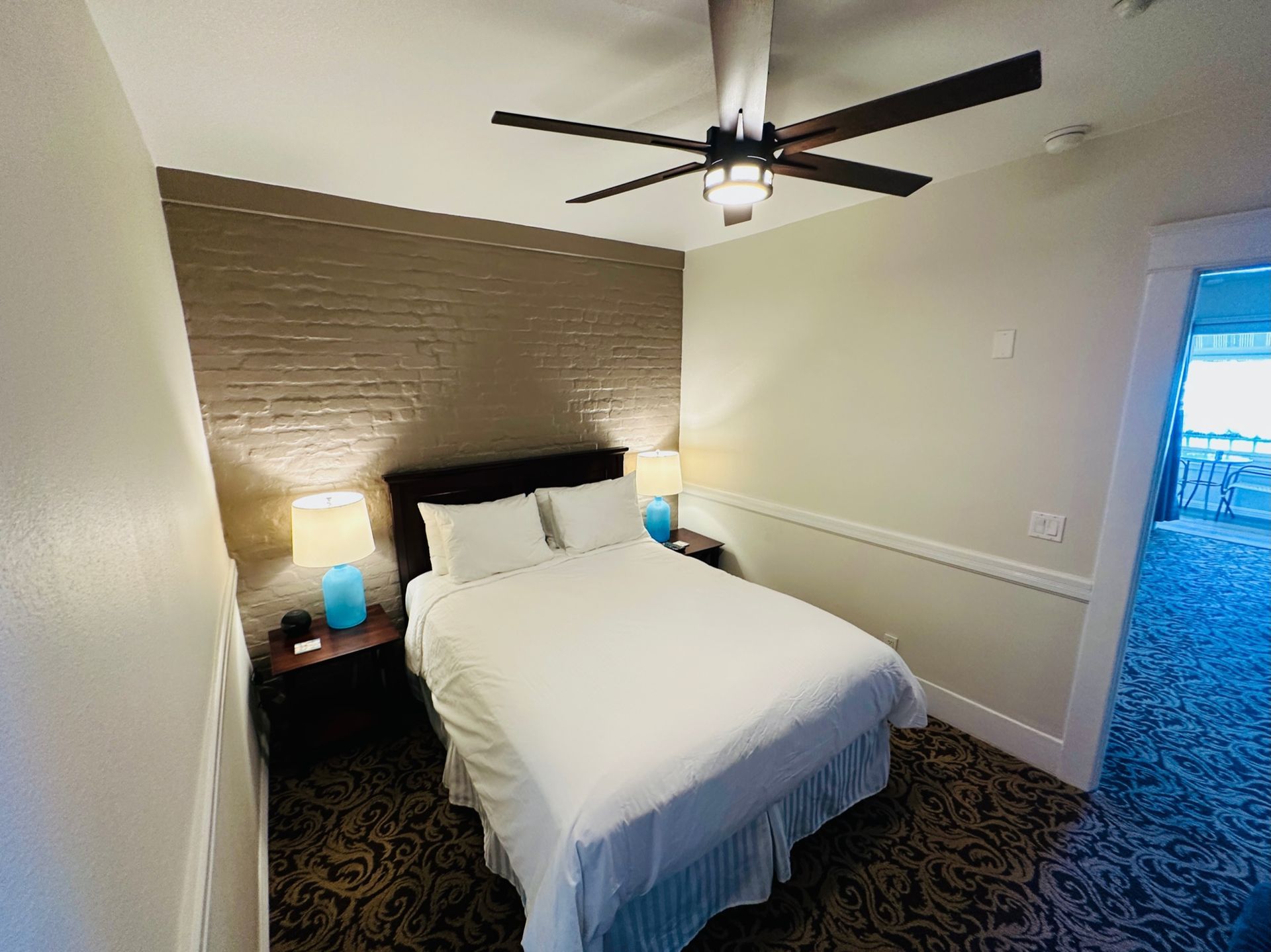 a hotel room with a king size bed and a ceiling fan .