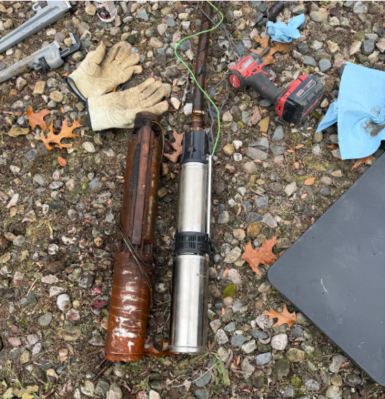 A well pump replacement with new and old pump lying on gravel. Tools and gloves are nearby in Cass County Michigan