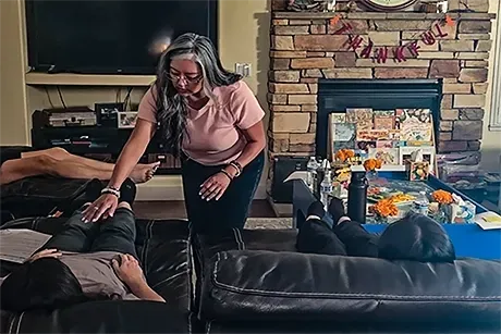 A woman is sitting in a lotus position on a yoga mat with chakras surrounding her.
