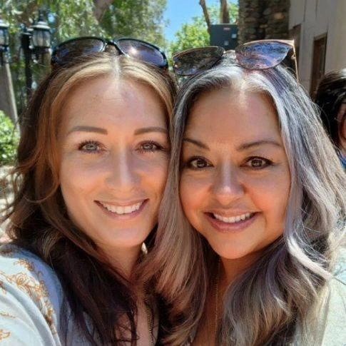 Two women are posing for a picture together and smiling for the camera.