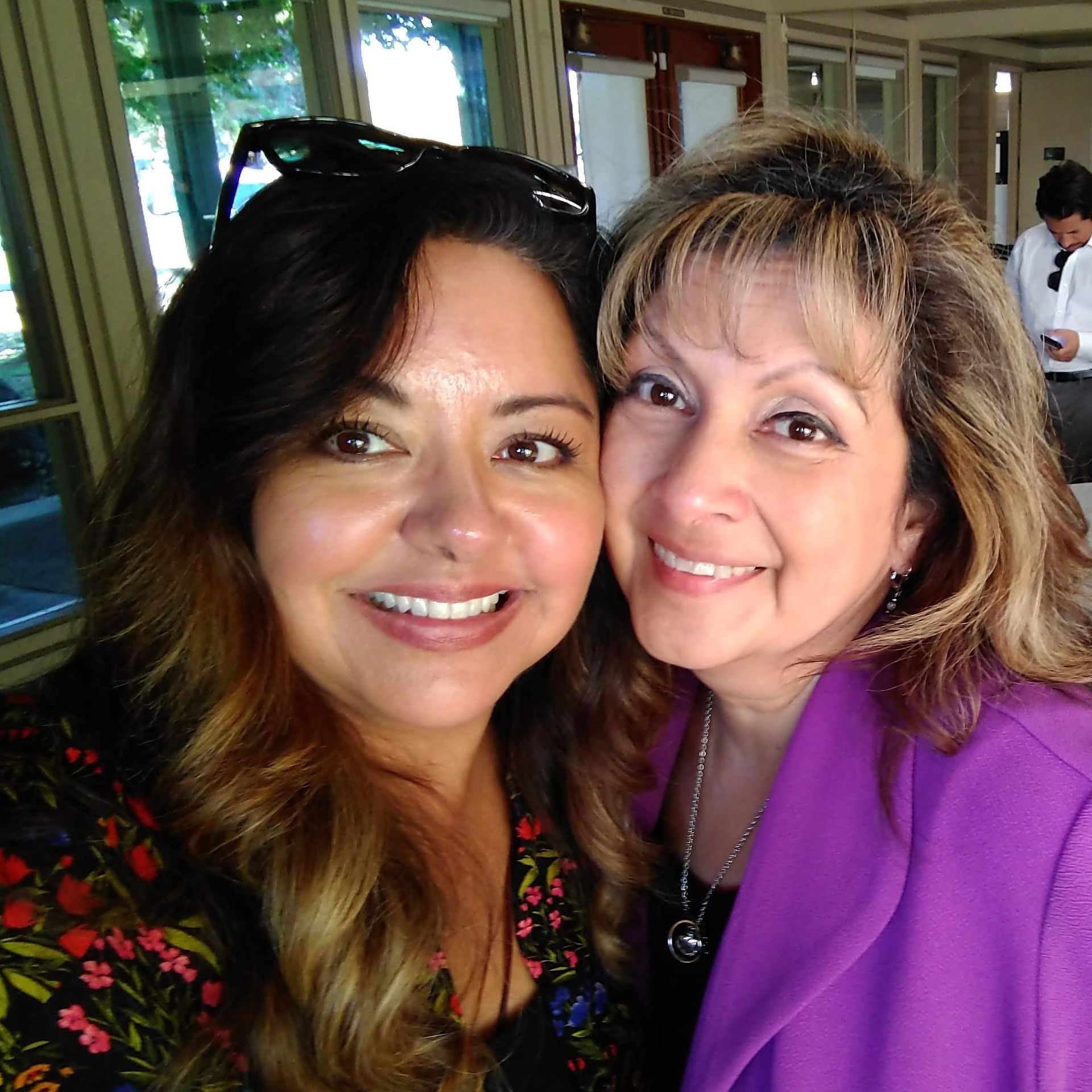 Two women are posing for a picture and one is wearing a purple jacket