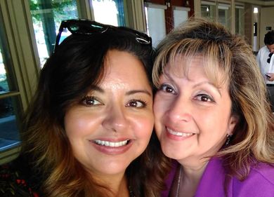 Two women are posing for a picture together and smiling for the camera.