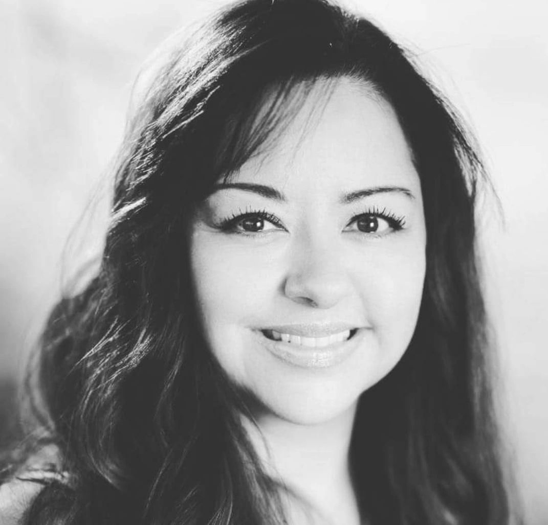 A woman with long hair is smiling in a black and white photo.