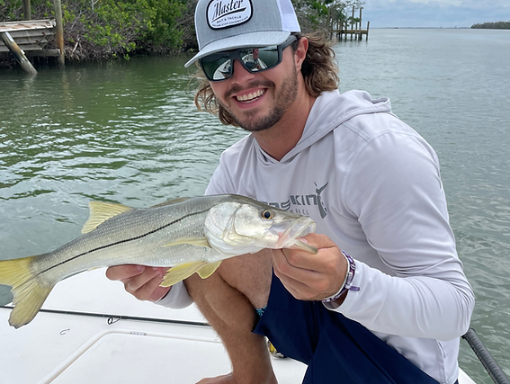 A man is kneeling on a boat holding a fish.