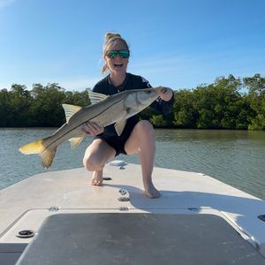 A woman is kneeling on a boat holding a large fish.