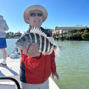 A man is holding a striped fish on a boat
