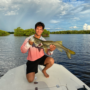 A man kneeling on a boat holding a large fish