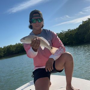 A man is sitting on a boat holding a fish.