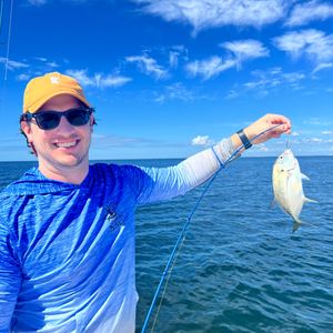 A man is holding a fish in his hand in the ocean.