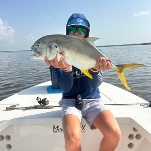 A man is sitting on a boat holding a fish