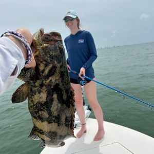 A woman is holding a large fish on a boat.
