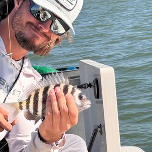 A man is holding a fish in his hand while sitting on a boat.