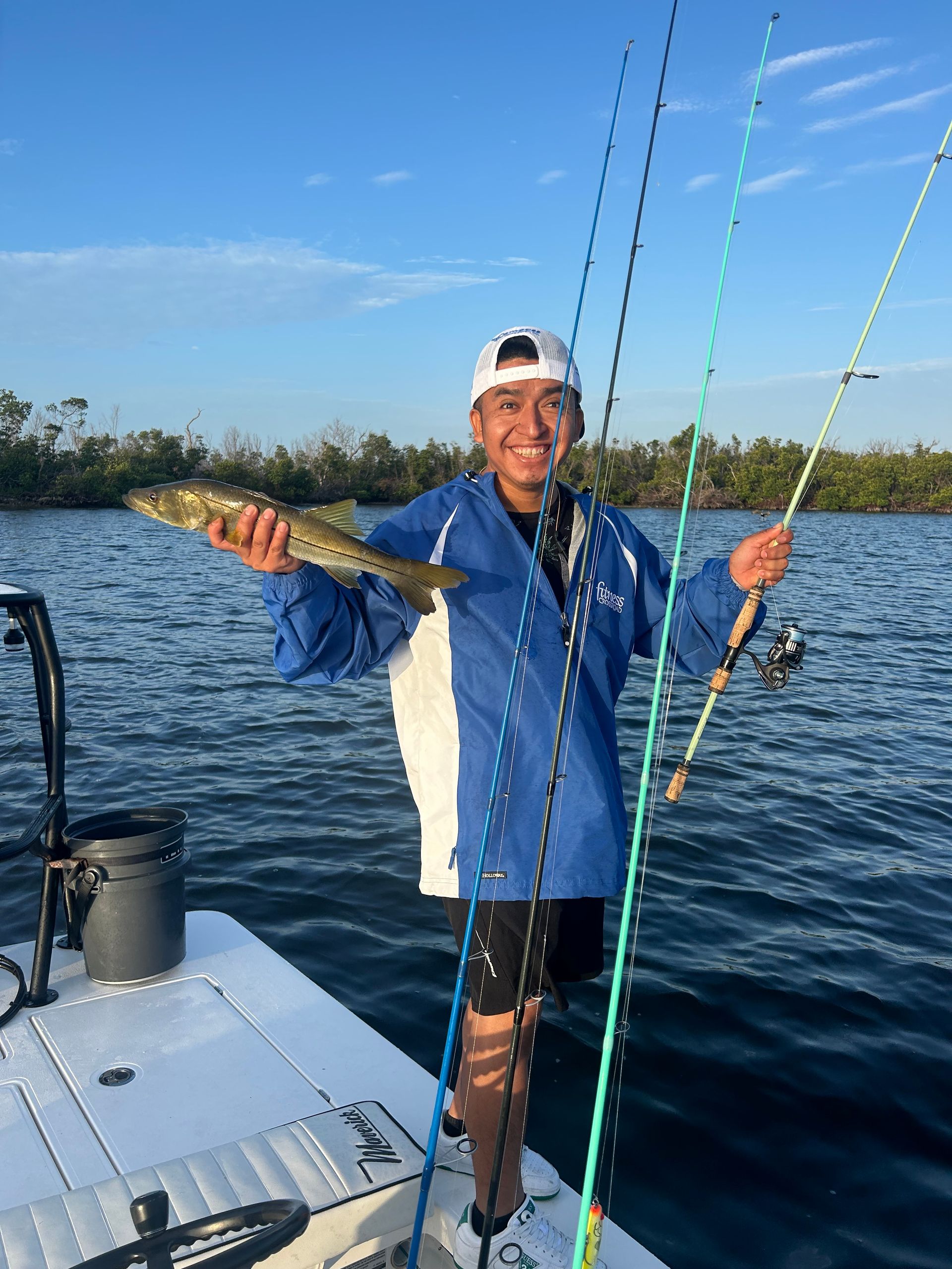 A man is standing on a boat holding a fish.