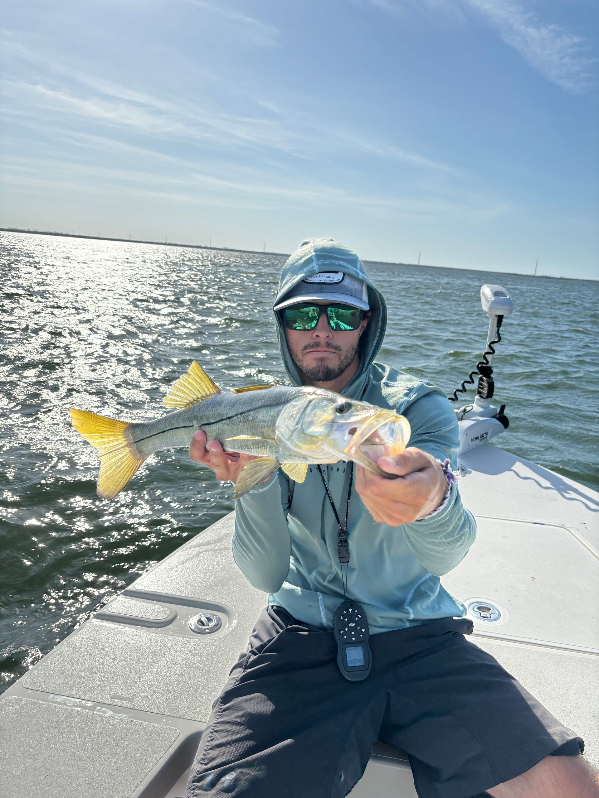 A man is sitting on a boat holding a fish.