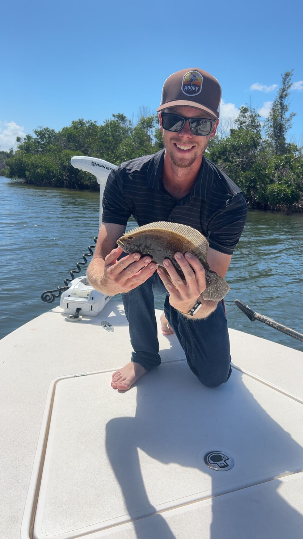 A man is kneeling on a boat holding a fish in his hands.